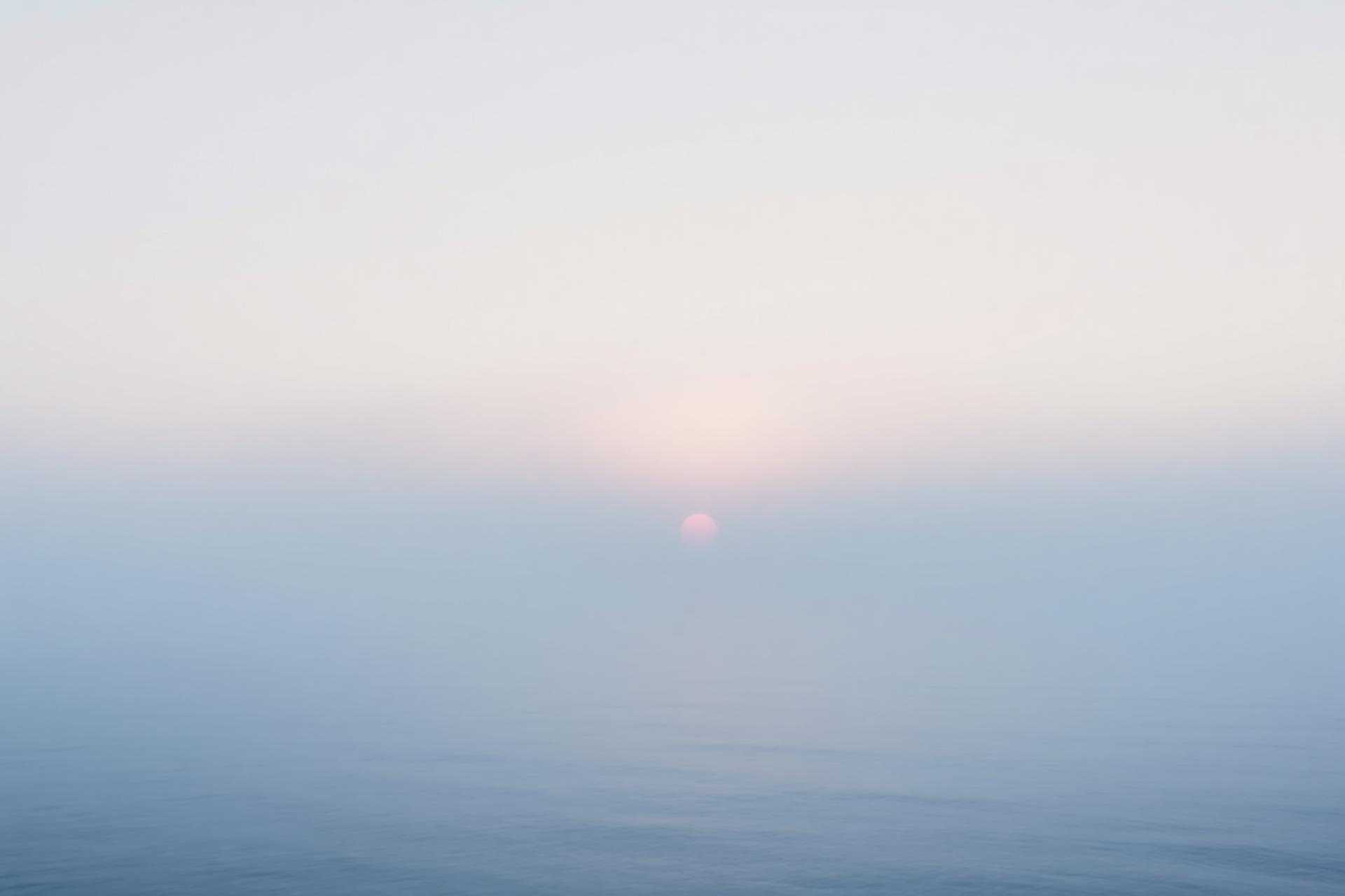 Soft ocean sunrise across still water